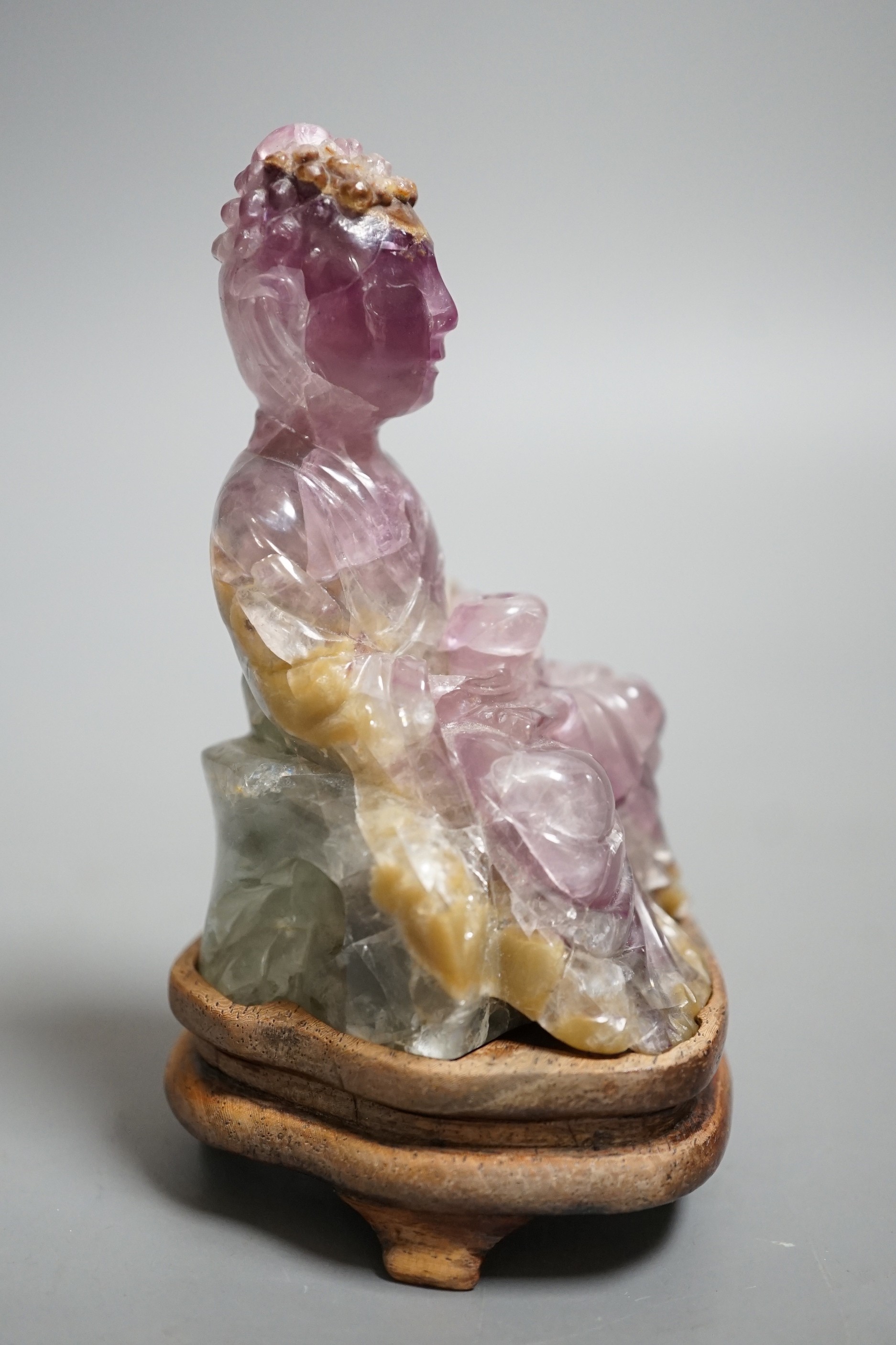 A 19th century amethyst and green quartz carving of a seated buddha on hardwood stand. Height 12cm